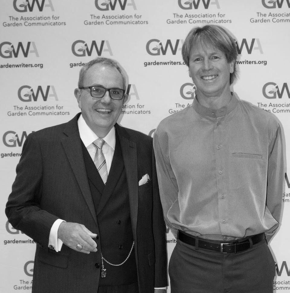 Paul Tukey, right, standing with another man in front of an Association for Garden Communicators backdrop